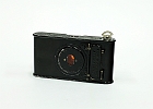 img 0002  Aparat produkowany w latach 1915 – 1926. Film zwojowy o szerokości 4 cm. Przesłona 1, 2, 3, 4 – opisana jako motywy: portret, średni, odległy obiekt. Czasy B, T 1/25 – 1/50 s. Odległość hiperfokalna . Miech w kolorze czarnym. Aparat w tylnej ściance posiadał podłużną otwieraną klapkę, po otwarciu której na boku zdjęcia można było wykonywać specjalnym rysikiem napisy.